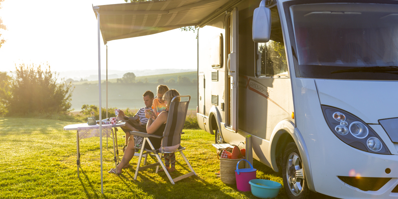 Gezin zit voor de camper op het terras met mooi uitzicht over zuid-limburg 