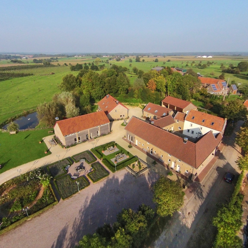 Bovenaanzicht van een grote boerderij met tuin en land eromheen. 