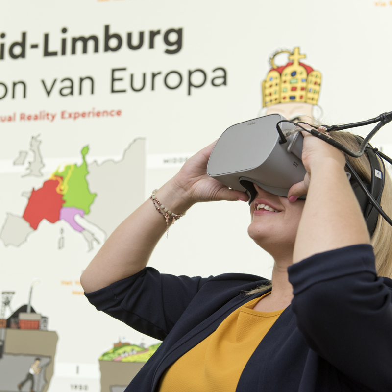 Bezoeker met een VR bril in de Experience Valkenburg met op de achtergrond de Bron van Europa