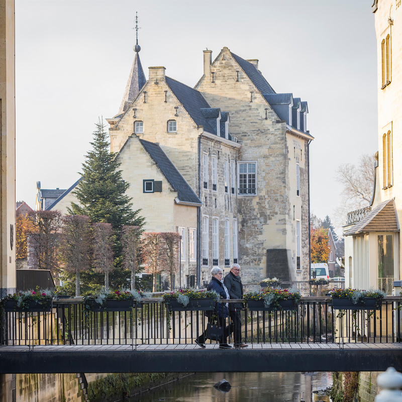 twee oudere mensen lopen over brug bij Geulpoort in de winter